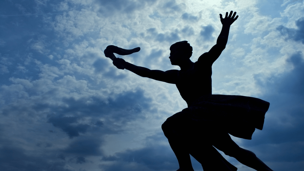 Silhouette of a torchbearer against a cloudy sky, representing the continuity of family legacy.